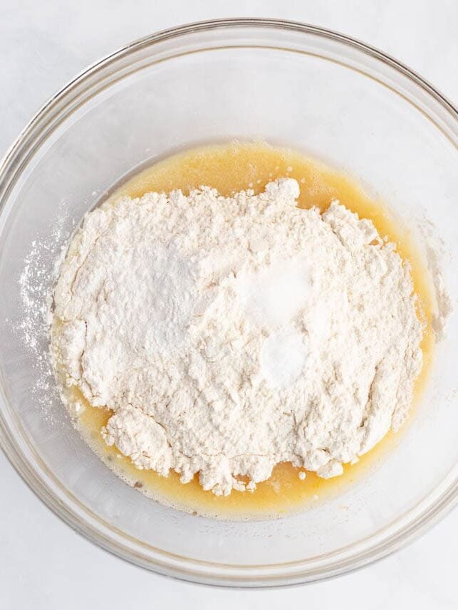 Adding flour and dry ingredients to the wet batter for strawberry quick bread.