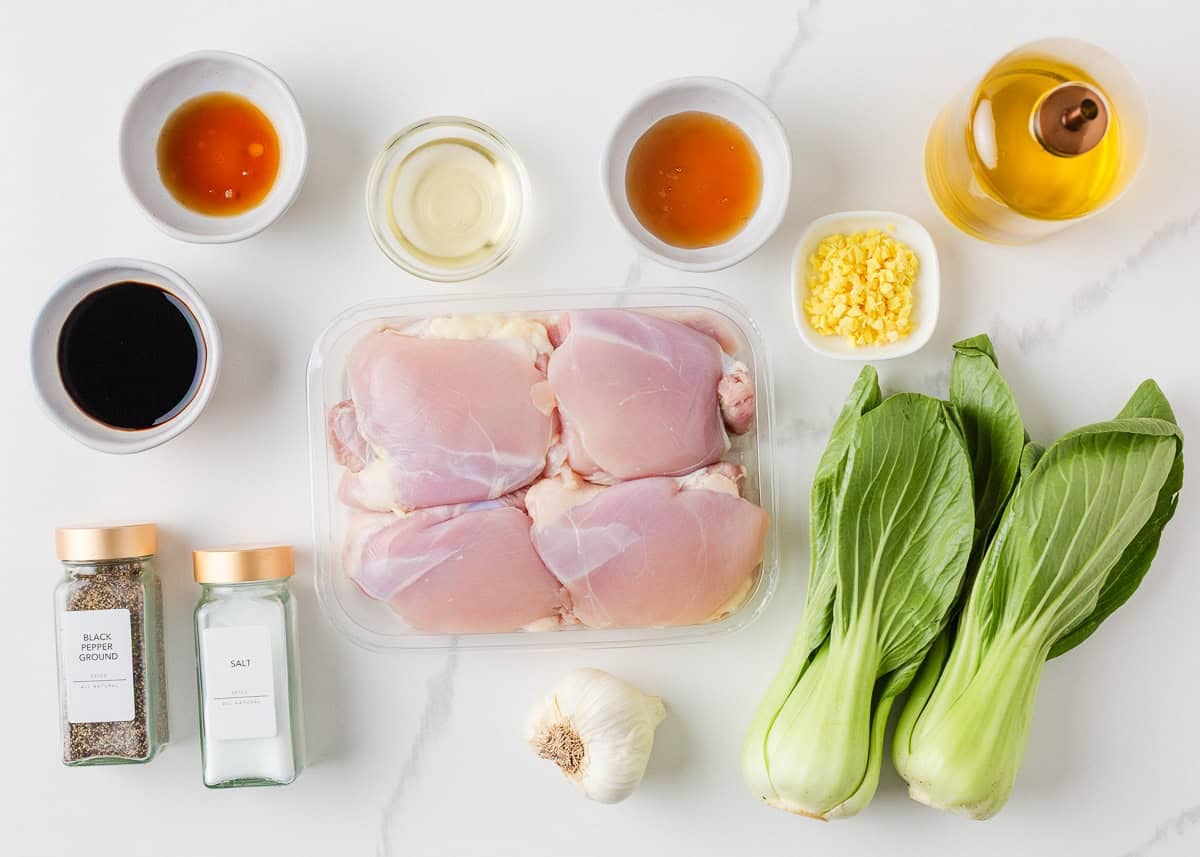 Ingredients for Asian chicken thighs including chicken, soy sauce, rice vinegar, sesame oil, honey, garlic, ginger and baby bok choy.