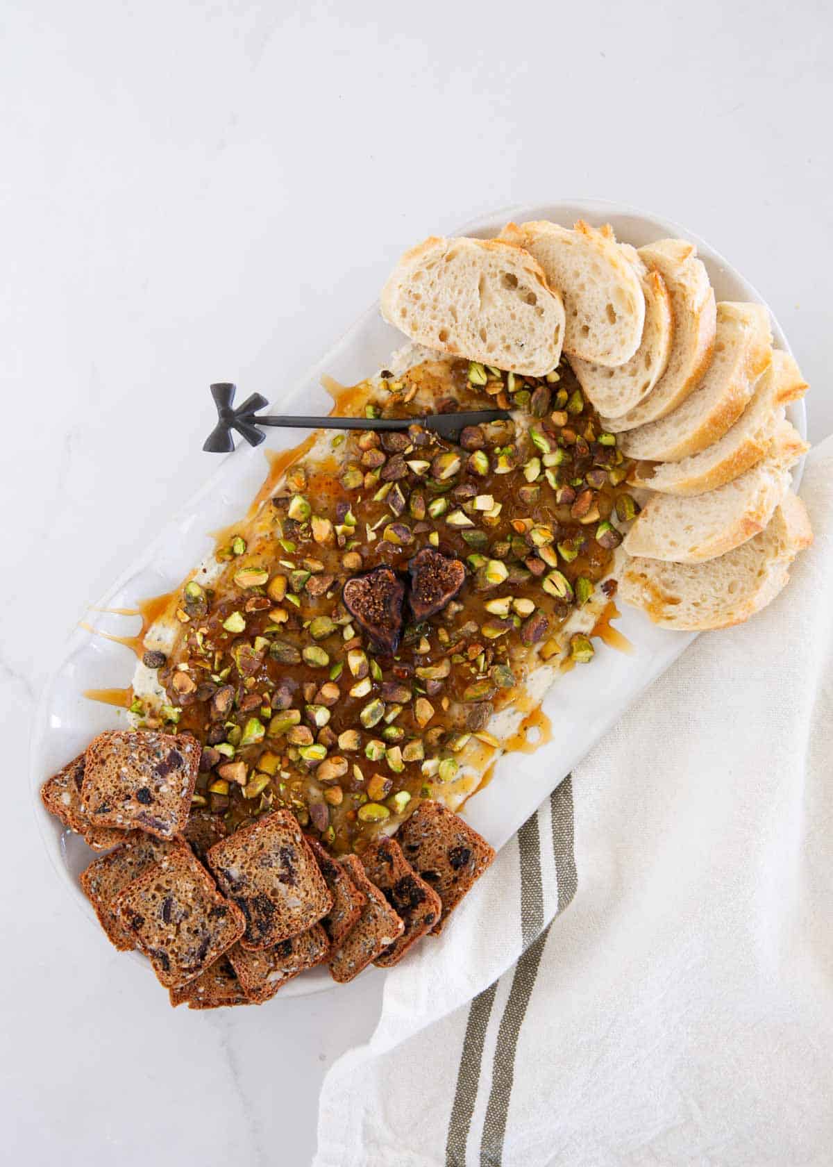 Boursin cheese fig dip with pistachios, hot honey, baguette slices and bread toasts.