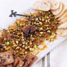 Boursin cheese fig dip with pistachios, hot honey, baguette slices and bread.