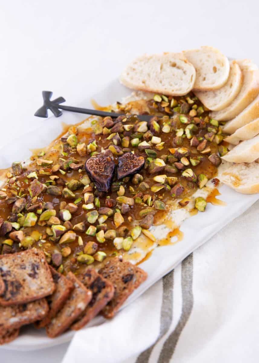 Close up of creamy Boursin fig dip with fig jam, chopped pistachios and bread.