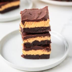 Stacked buckeye brownies showing layers of chocolate brownie, peanut butter filling and smooth chocolate ganache.