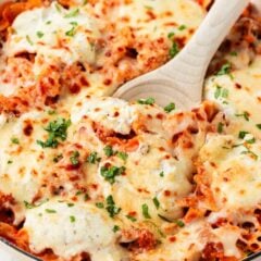 Skillet lasagna with mini farfalle pasta, Italian sausage, marinara sauce, and melted mozzarella and parmesan cheese, garnished with fresh parsley.