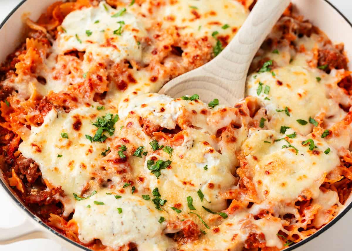 This easy one-pan skillet lasagna comes together on the stovetop in under an hour, with the same bubbly, saucy, cheesy comfort of the classic baked version. Skillet lasagna with mini farfalle pasta, Italian sausage, marinara sauce, and melted mozzarella and parmesan cheese, garnished with fresh parsley.