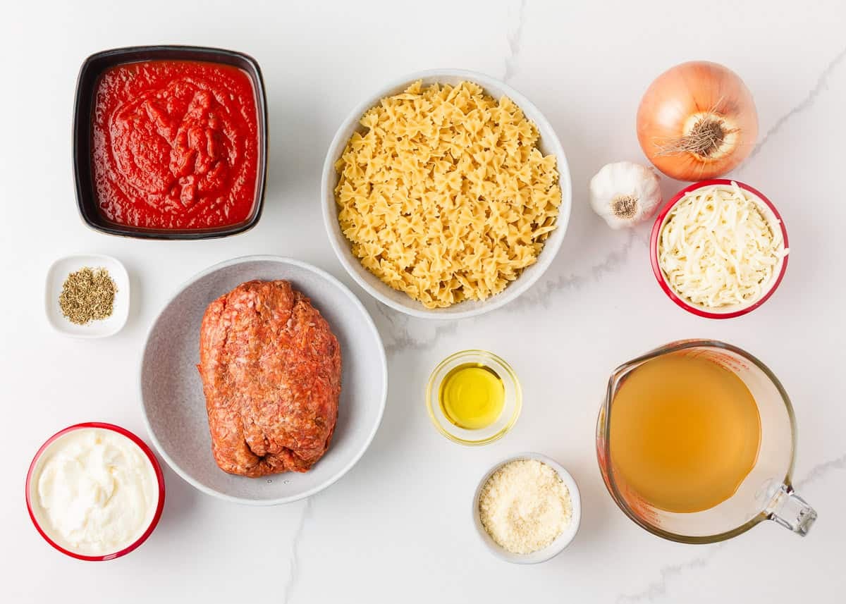 This easy one-pan skillet lasagna comes together on the stovetop in under an hour, with the same bubbly, saucy, cheesy comfort of the classic baked version. Ingredients for skillet lasagna including mini farfalle pasta, Italian sausage, marinara sauce, ricotta, mozzarella, parmesan, onion, garlic, and broth.