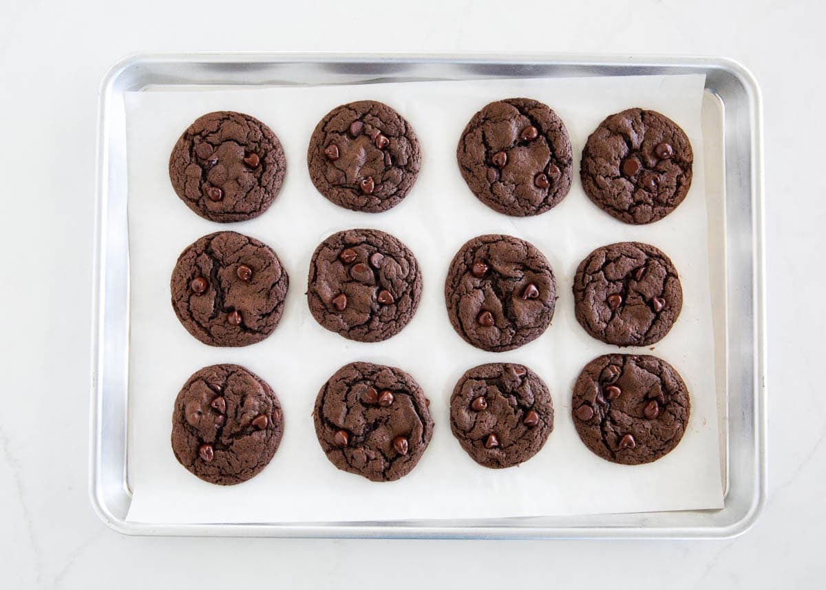 Freshly baked chocolate cake mix cookies with chocolate chips arranged on a parchment-lined baking sheet.