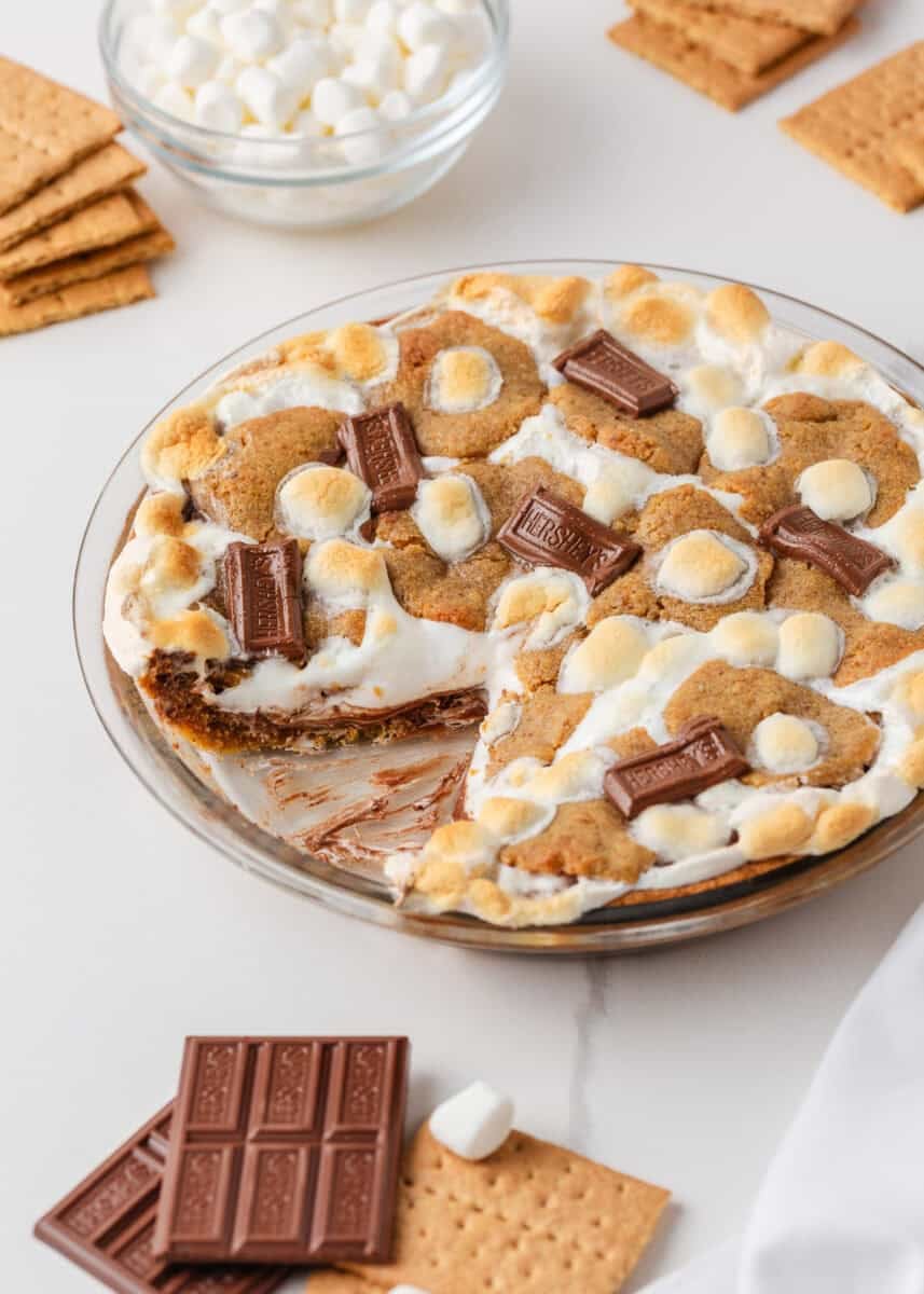 Easy s’mores pie in a glass pie dish with toasted marshmallows, Hershey chocolate, and graham cracker cookie crust.