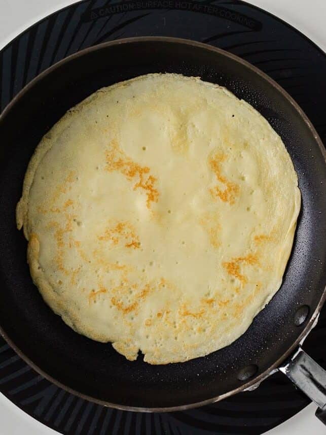 Cooked crepe with golden brown spots in a nonstick skillet.