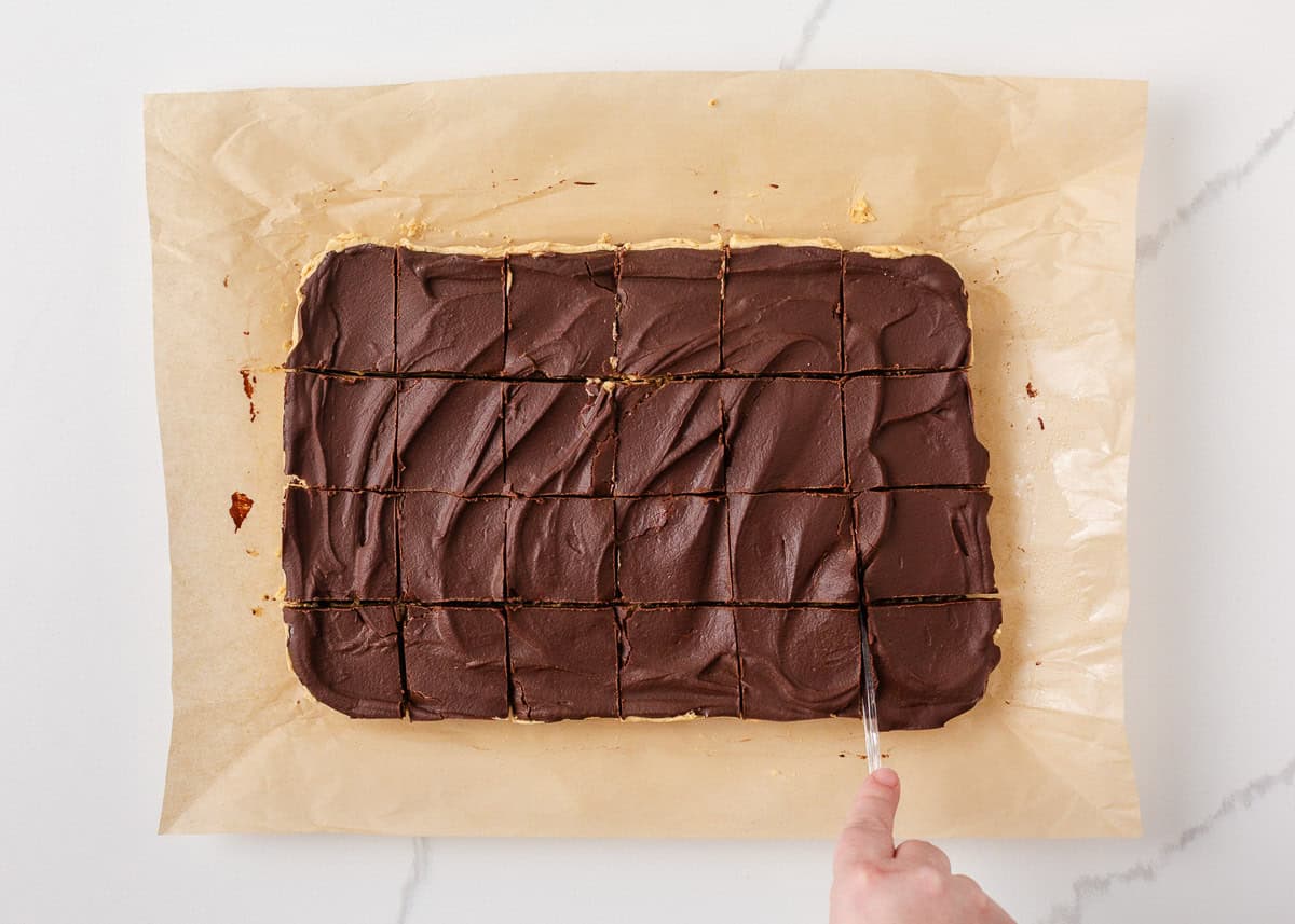 Pan of buckeye brownies sliced into squares on parchment paper.