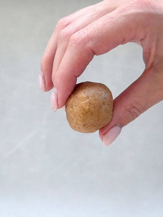 These Butterfinger balls are bite-sized no-bake truffles with crushed Butterfinger candy and graham crackers folded into the filling, then dipped in chocolate. An irresistible sweet treat! Showing a butterfinger ball before dipping in chocolate.