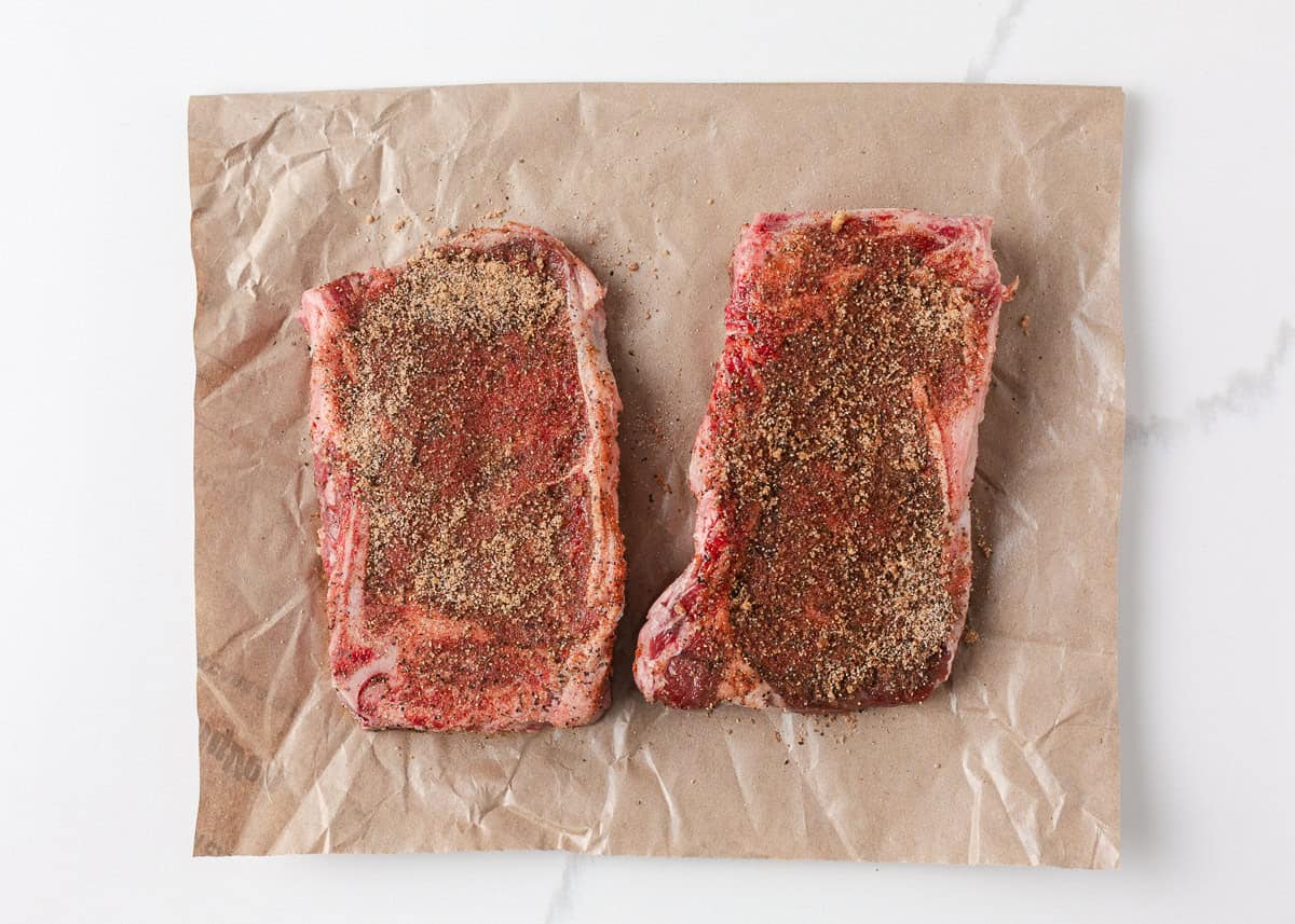 Bone-in steaks seasoned with homemade dry rub before grilling.