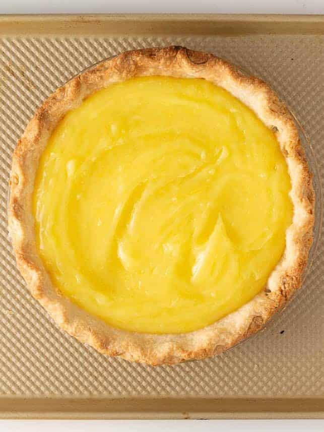 Warm lemon filling spread into a blind baked pie crust for lemon meringue pie.