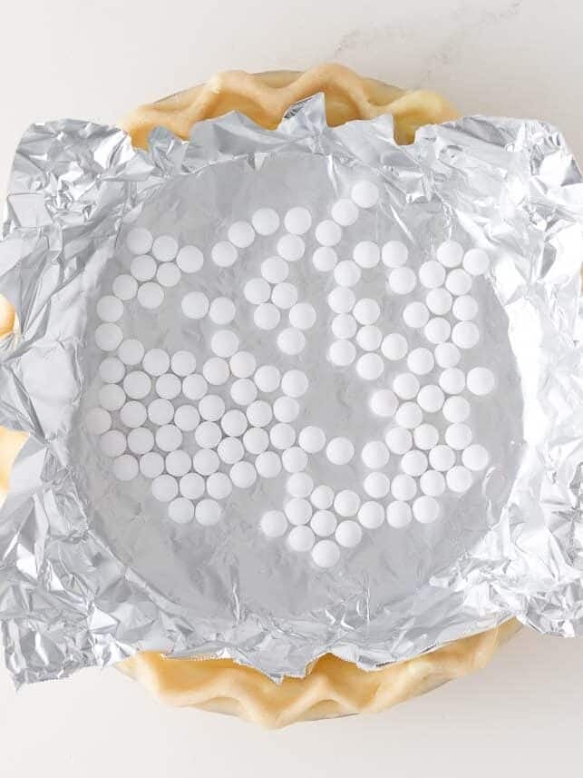 Pie crust lined with foil and pie weights before blind baking.
