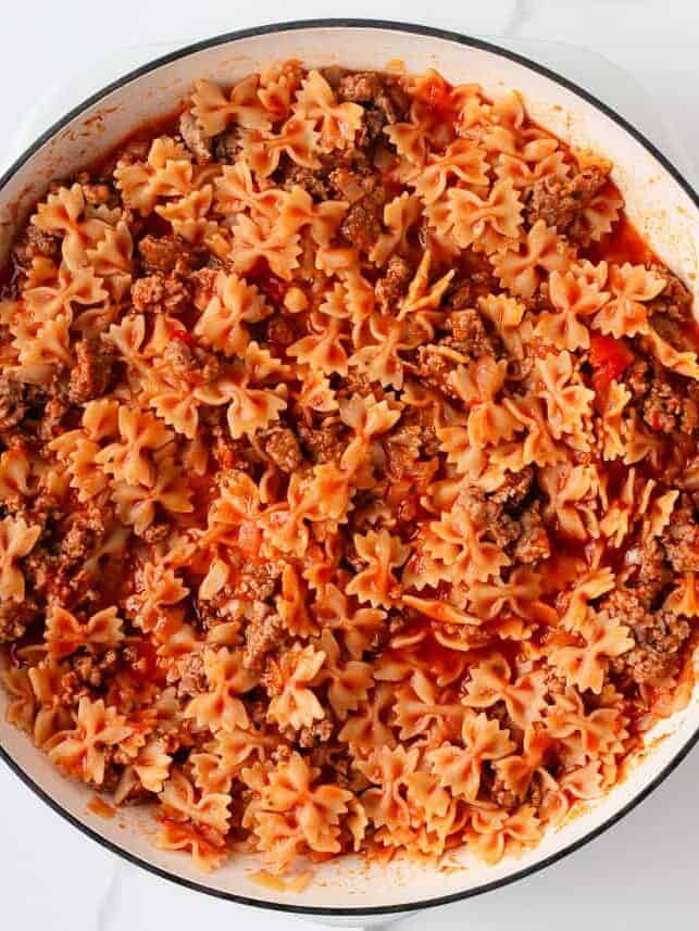 This easy one-pan skillet lasagna comes together on the stovetop in under an hour, with the same bubbly, saucy, cheesy comfort of the classic baked version. Mini farfalle pasta cooking in sauce for quick and easy skillet lasagna dinner.