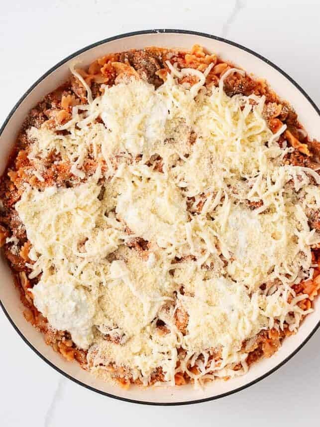 This easy one-pan skillet lasagna comes together on the stovetop in under an hour, with the same bubbly, saucy, cheesy comfort of the classic baked version. Adding ricotta, mozzarella, and parmesan cheese to skillet lasagna before melting.