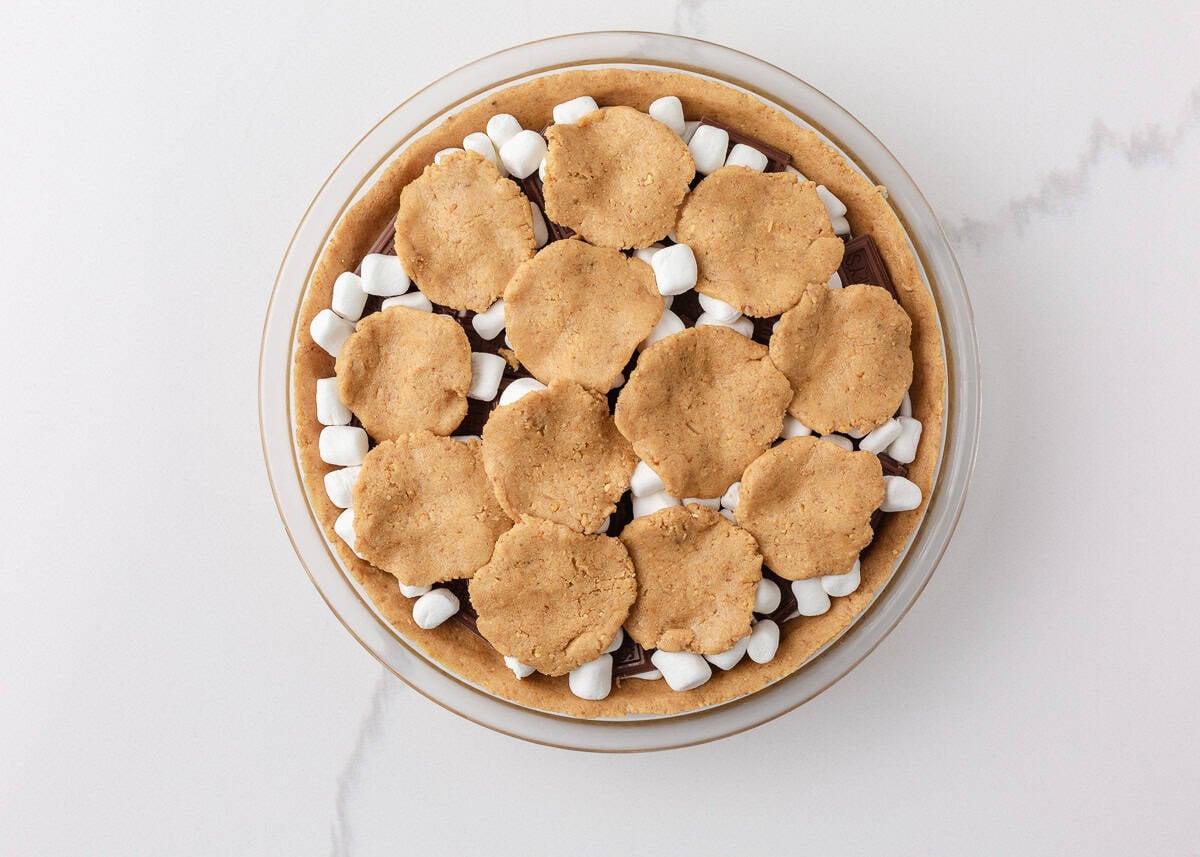 S’mores pie before baking with Hershey chocolate, mini marshmallows, and pieces of graham cracker dough layered on top.