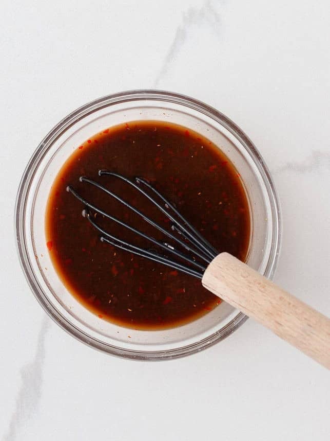 This easy Thai basil chicken recipe is bold, savory, and ready in under 30 minutes. It's everything you love about your favorite Thai food, made right at home! Thai basil chicken sauce with soy sauce, chili garlic sauce, and seasonings in a bowl.