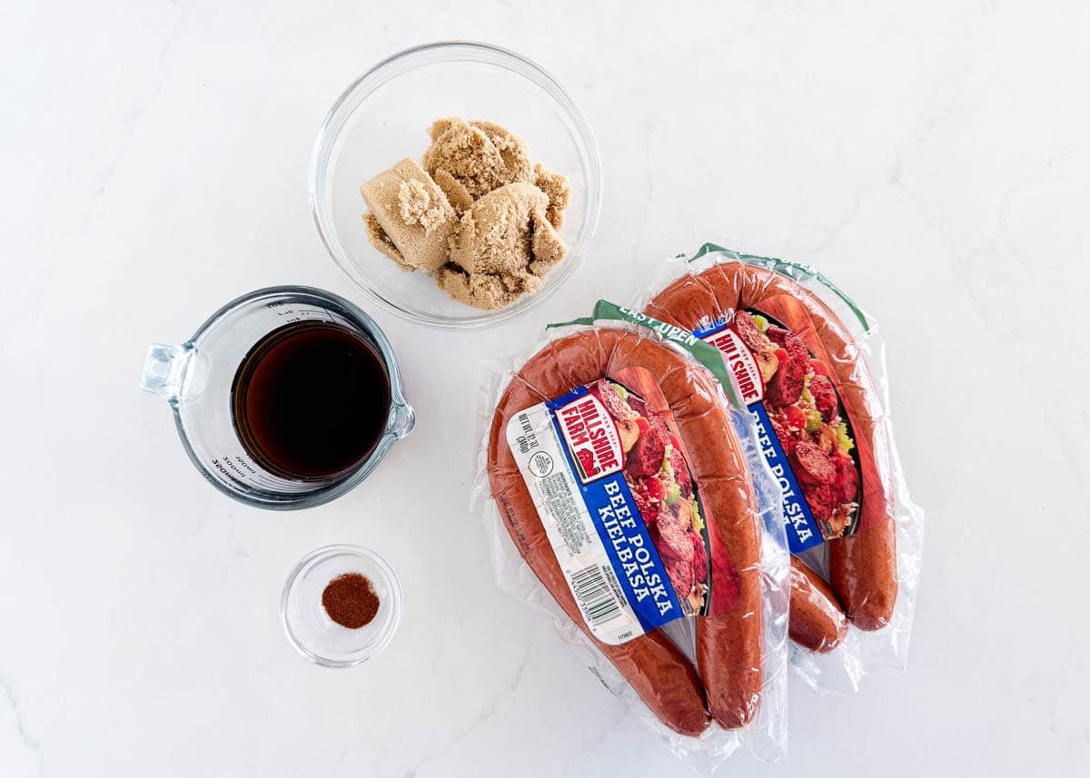Ingredients for brown sugar kielbasa bites including kielbasa, brown sugar, cola and chili powder.