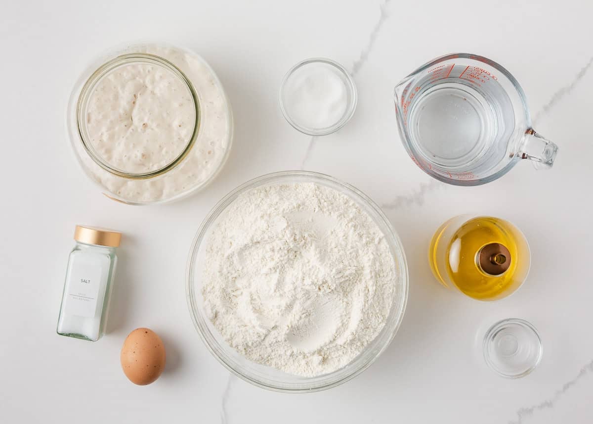 Sourdough French bread ingredients including starter, flour, water, salt, sugar, olive oil, and egg.