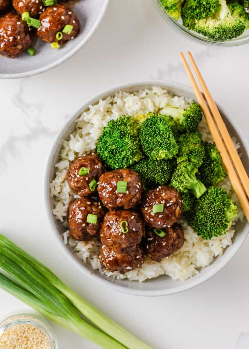 Sticky pork meatballs over white rice with steamed broccoli, green onions and sesame seeds.