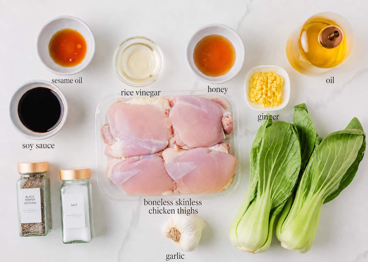 Ingredients for Asian chicken thighs including chicken, soy sauce, rice vinegar, sesame oil, honey, garlic, ginger and baby bok choy.