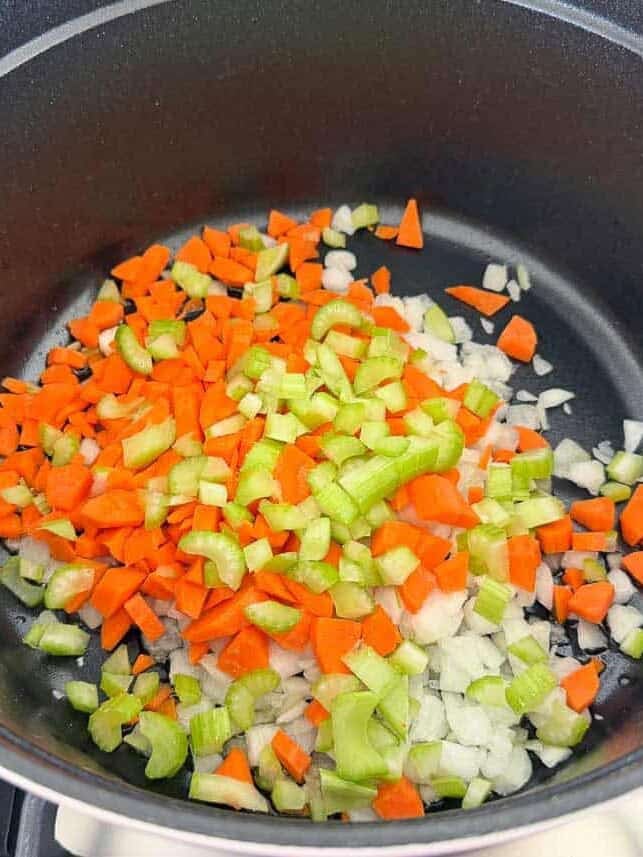 Diced onion, carrots and celery sautéing in a pot for homemade black bean soup.