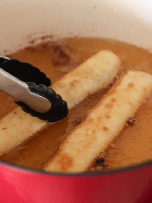 Chicken flautas frying in hot oil until golden brown.