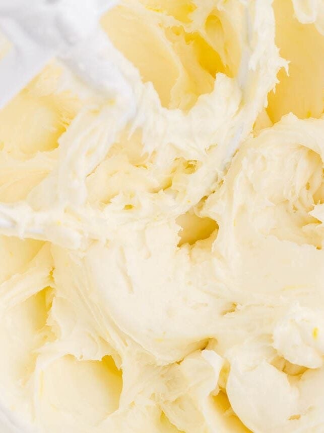 Whipped lemon cream cheese frosting in a glass bowl with the mixer beater.