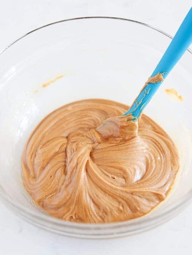 Smooth peanut butter, honey, and vanilla stirred together in a glass bowl.