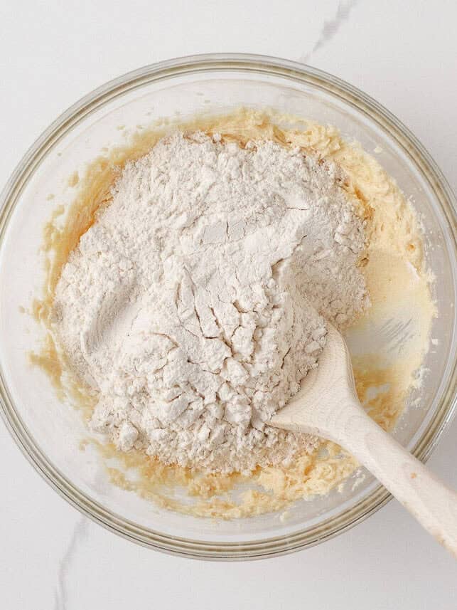 Adding flour to the mixing bowl to form orange cookie dough.