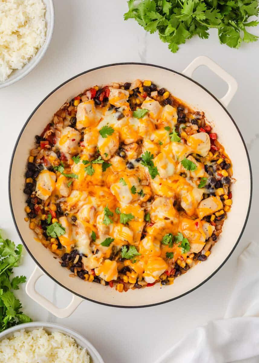 Overhead view of Santa Fe chicken skillet with melted cheese, black beans, corn and fresh cilantro.