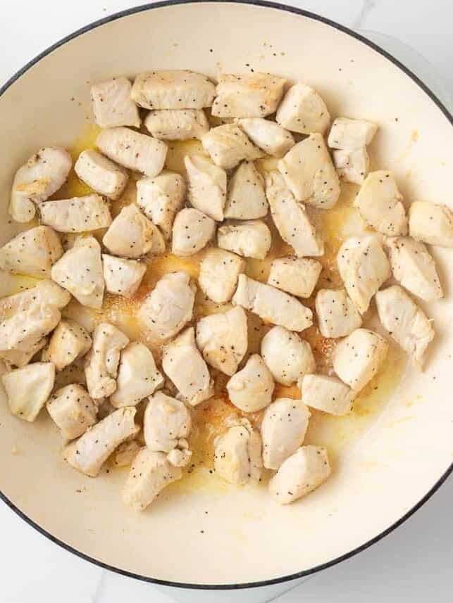 Bite-sized chicken pieces browning in a skillet.