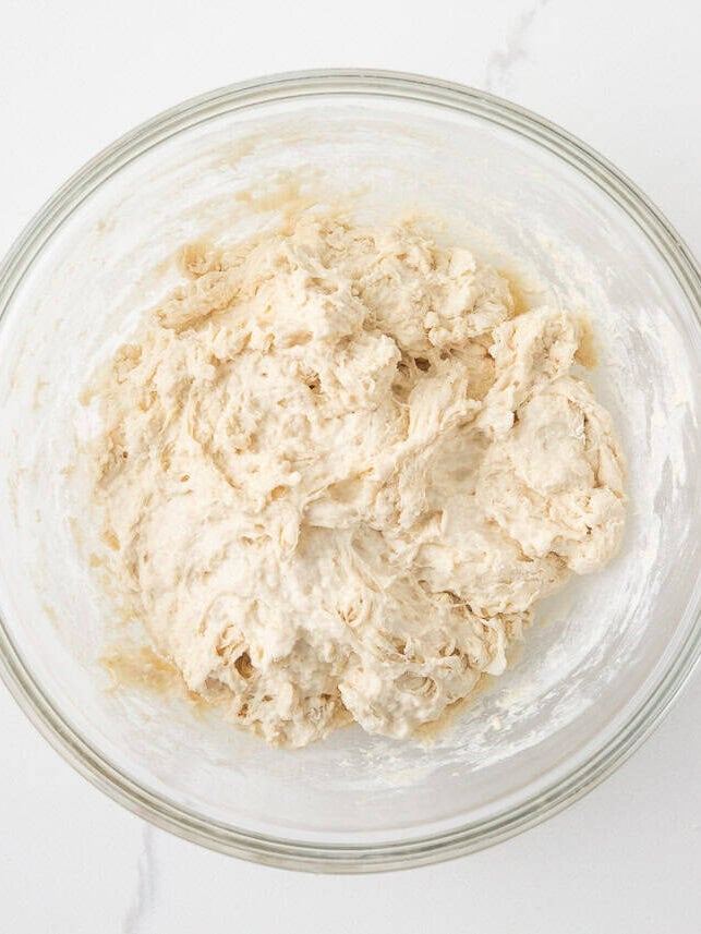 Sticky sourdough French bread dough mixed in a glass bowl before kneading.
