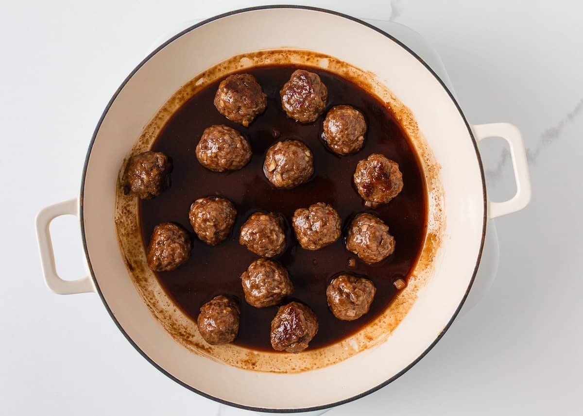 Sticky pork meatballs simmering in a glossy sweet and savory sauce.