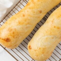 Close-up of golden baked sourdough French bread loaves on a cooling rack.