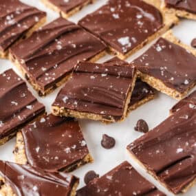 Viral cookie dough bark broken into pieces with chocolate chips and flaky sea salt on counter.