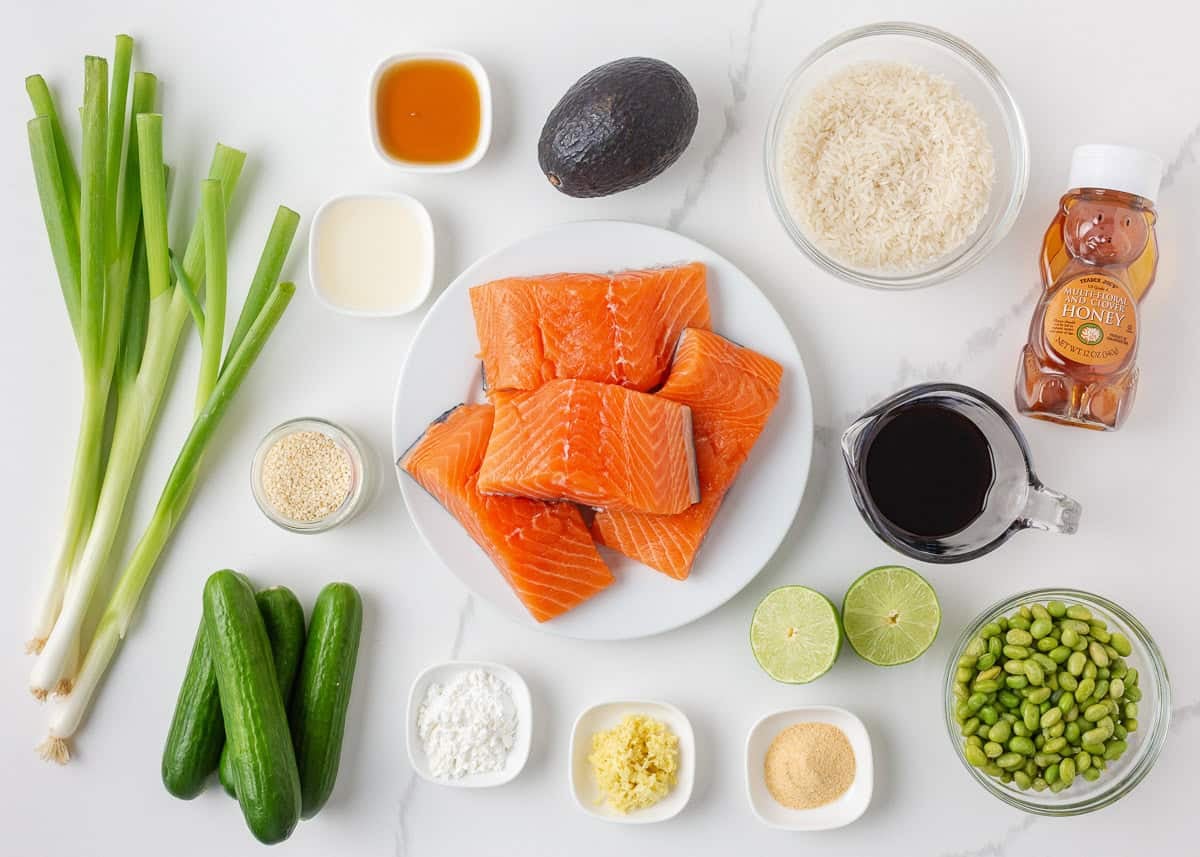 Ingredients for teriyaki salmon bowls, including fresh salmon, rice, avocado, cucumbers, edamame, green onions and homemade teriyaki glaze.