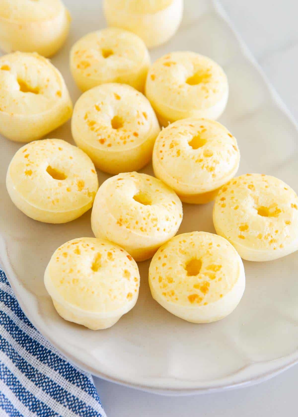 Close-up of golden Brazilian cheese bread bites on a serving plate.