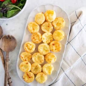 Brazilian cheese bites served on a platter with a fresh green salad.