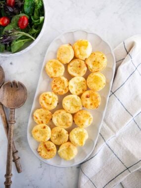 Brazilian cheese bites served on a platter with a fresh green salad.