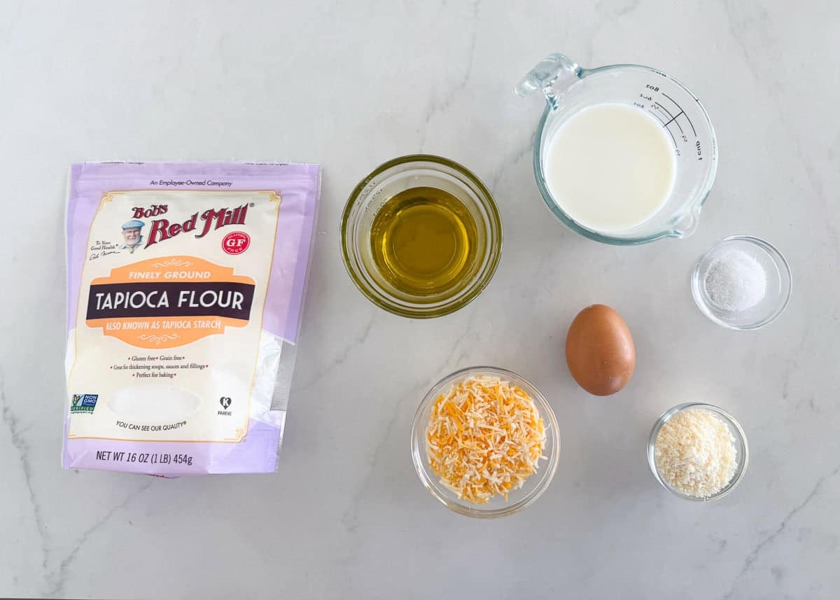 Ingredients for Brazilian cheese bites including tapioca flour, cheese, milk, egg and olive oil.