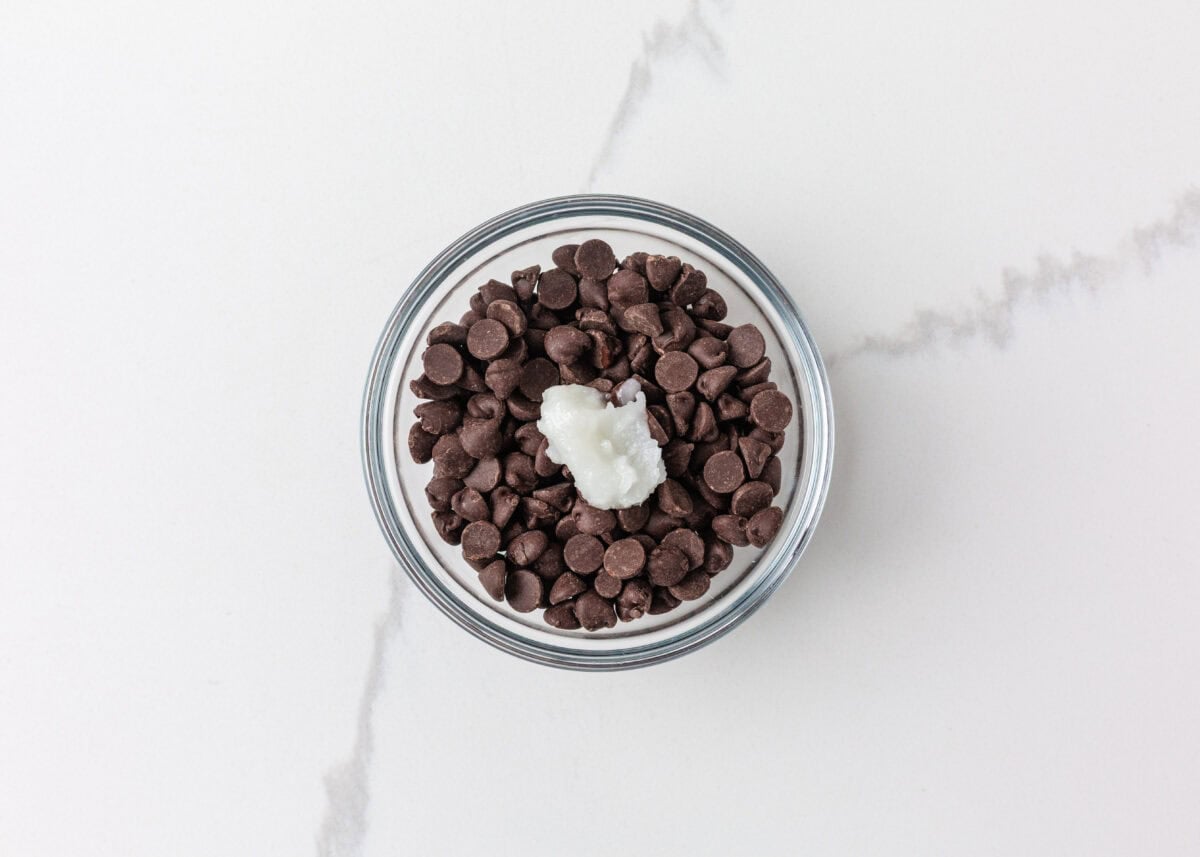 Chocolate chips and coconut oil in a bowl for making cookie dough bark topping.