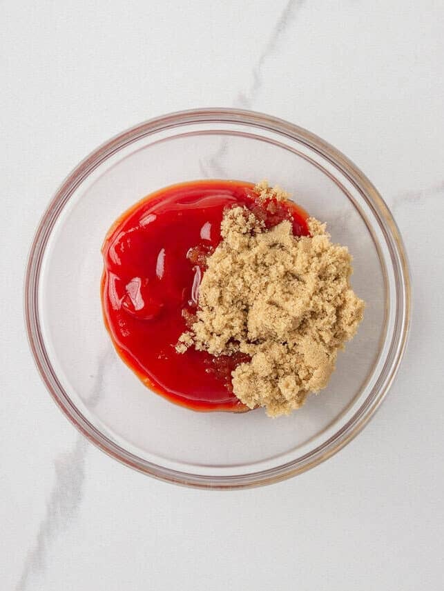 Ketchup and brown sugar in a glass bowl for making a sweet meatloaf glaze.