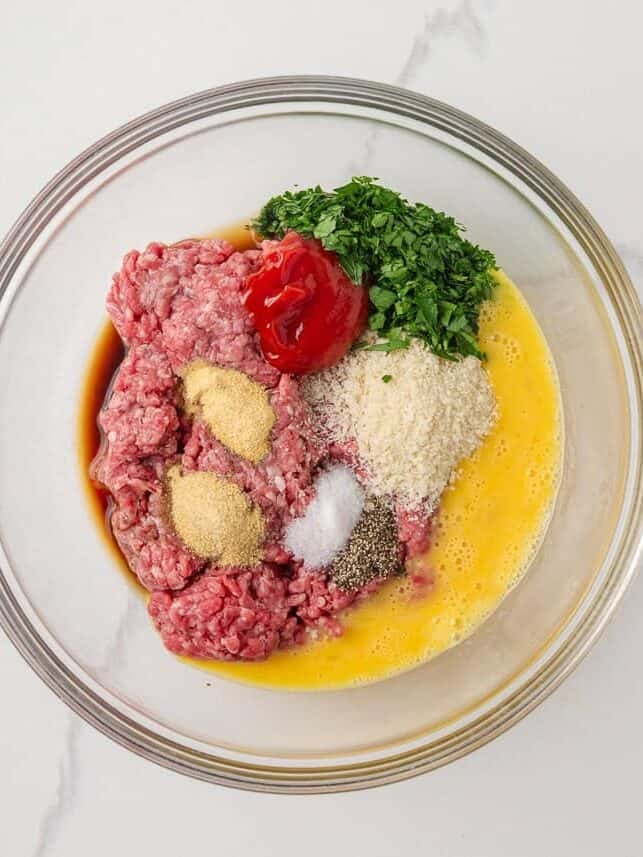 Ground beef mixture with parsley, breadcrumbs and seasonings ready to shape into mini meatloaves.