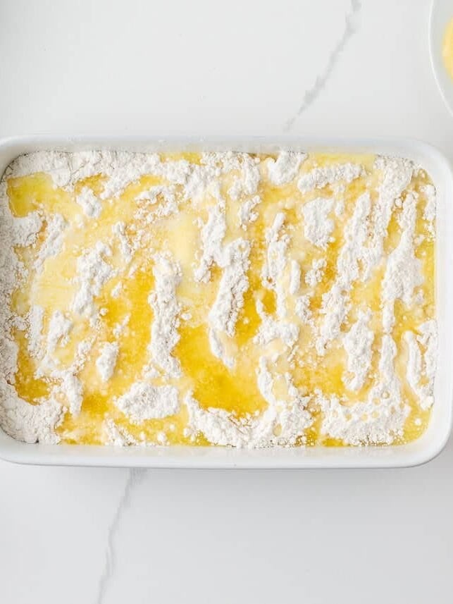 Melted butter drizzled over dry cake mix and crushed pineapple in a casserole dish.
