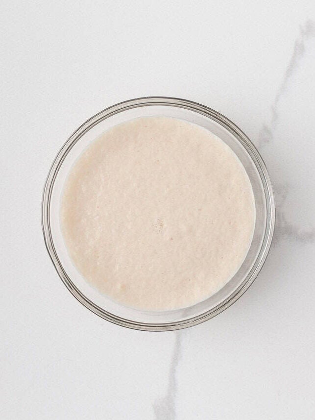 Foamy active dry yeast mixture in a small glass bowl.