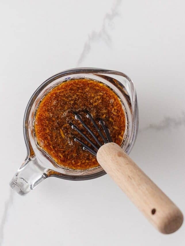 Homemade teriyaki sauce whisked with ginger and seasonings in a glass measuring cup.