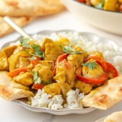 Coconut curry chicken served over white rice with naan and fresh cilantro.