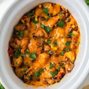 Close-up of cheesy crockpot cowboy casserole with potatoes, ground beef, black beans and corn.