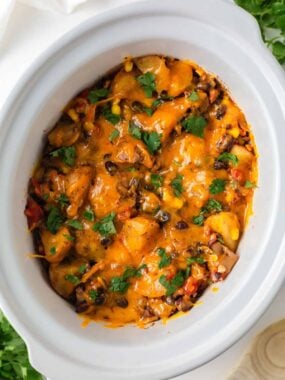 Close-up of cheesy crockpot cowboy casserole with potatoes, ground beef, black beans and corn.